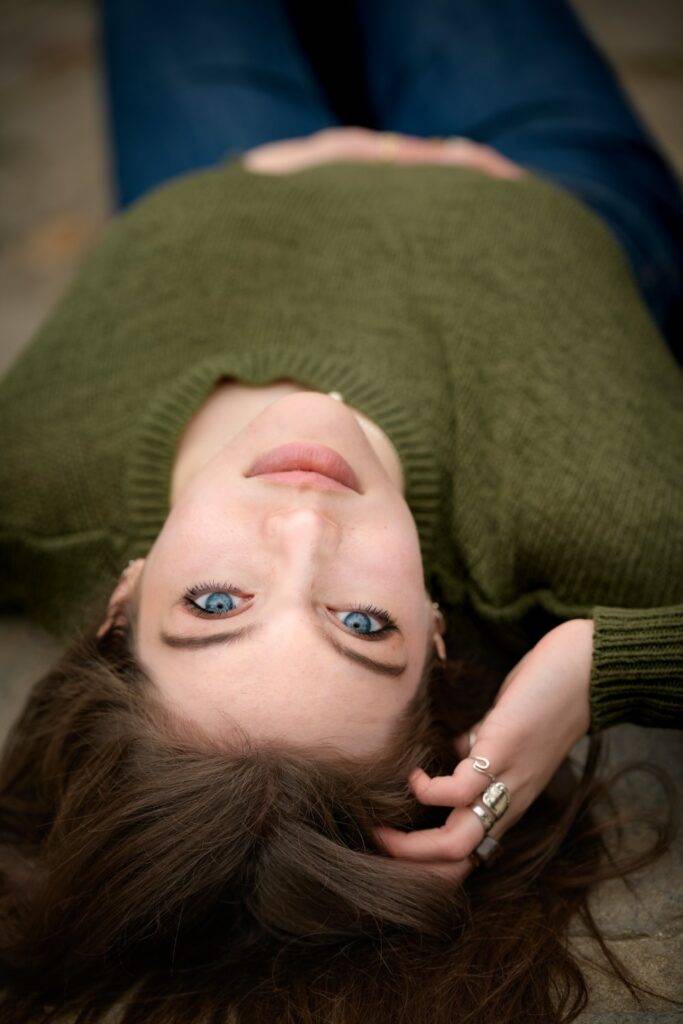 high school senior with striking blue eyes laying upside down unique portraits taken by Krista Nutter Photography