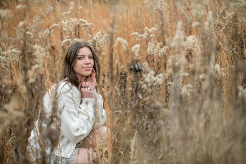 senior girl in a white dress kneeling in a field of tall grass at the Cincinnati Nature Center senior portrait by Krista Nutter Photography Cincinnati