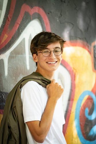 senior boy with coat over shoulder leaning on graffiti wall senior portrait by Krista Nutter Photography Cincinnati