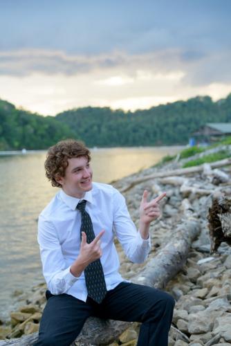 KristaNutterPhotography8504961 senior boy sitting in shirt and tie on rocky lakeshore beach destination portrait sessions