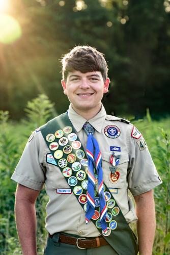 senior boy in a boy scout uniform standing in a field of tall grasses at sunset at the Cincinnati Nature Center senior portrait by Krista Nutter Photography Cincinnati