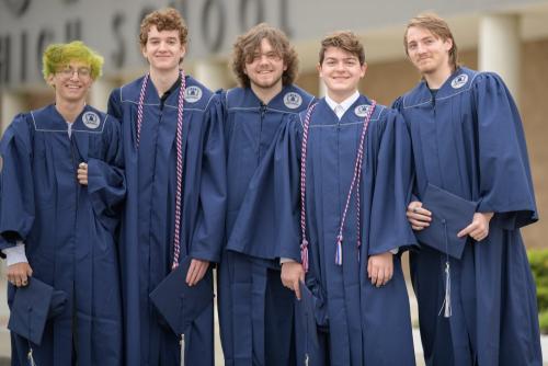 five senior boys in blue graduation caps and gowns smiling in front of a high school senior portrait by Krista Nutter Photography Cincinnati