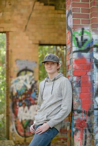 senior boy in an abandoned industrial building standing in front of graffiti senior portrait by Krista Nutter Photography Cincinnati