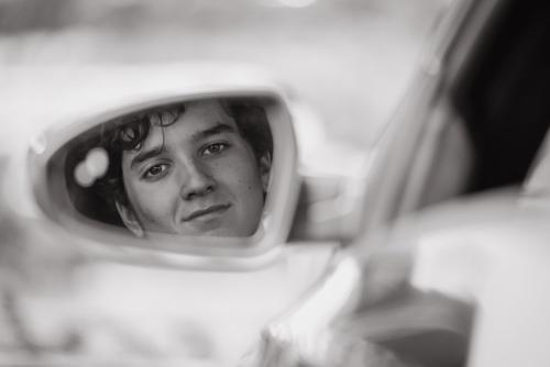 black and white image of a senior boy's reflection looking at the camera in a car side mirror senior portrait by Krista Nutter Photography Cincinnati