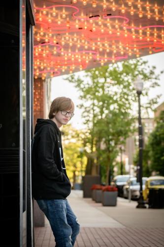 KristaNutterPhotography_8509225 senior boy in hip hop outfit near a lighted theater marquis headshots and personal branding portraits by Krista Nutter Photography Cincinnati