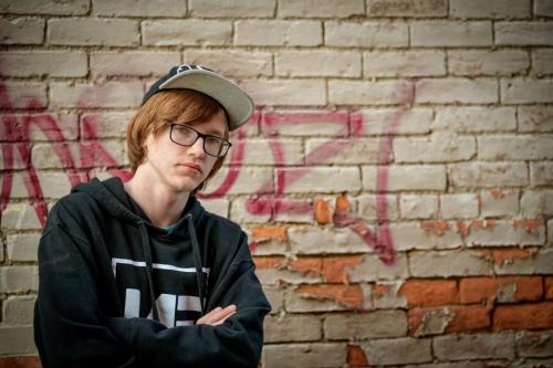 KristaNutterPhotography_8509310 senior boy in hip hop outfit in front of graffiti brick wall headshots and personal branding portraits by Krista Nutter Photography Cincinnati