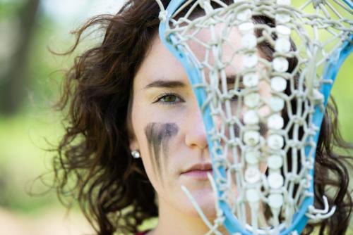 girl lacrosse player looking though the mesh of the stick head senior sports portrait by Krista Nutter Photography Cincinnati
