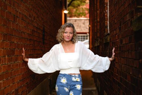 senior girl in white shirt standing in the middle of a brick alley in a sassy pose senior portrait by Krista Nutter Photography Cincinnati