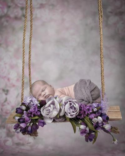 KristaNutterPhotographyvvvvvvvvMG 1772-Edit-2swing newborn from side laying on stomach in purple floral wreath on a wooden swing family and pet portraits by Krista Nutter Photography