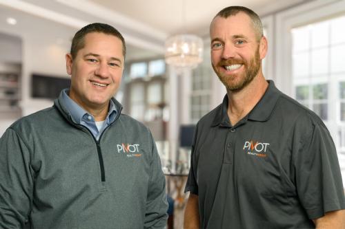 two men in gray Pivot Realty polo shirts standing in stylish living room headshots and personal branding portraits by Krista Nutter Photography Cincinnati